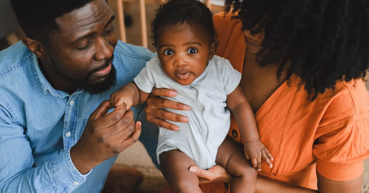 Des parents aimants tenant un adorable bébé dans un environnement chaleureux et intime.
