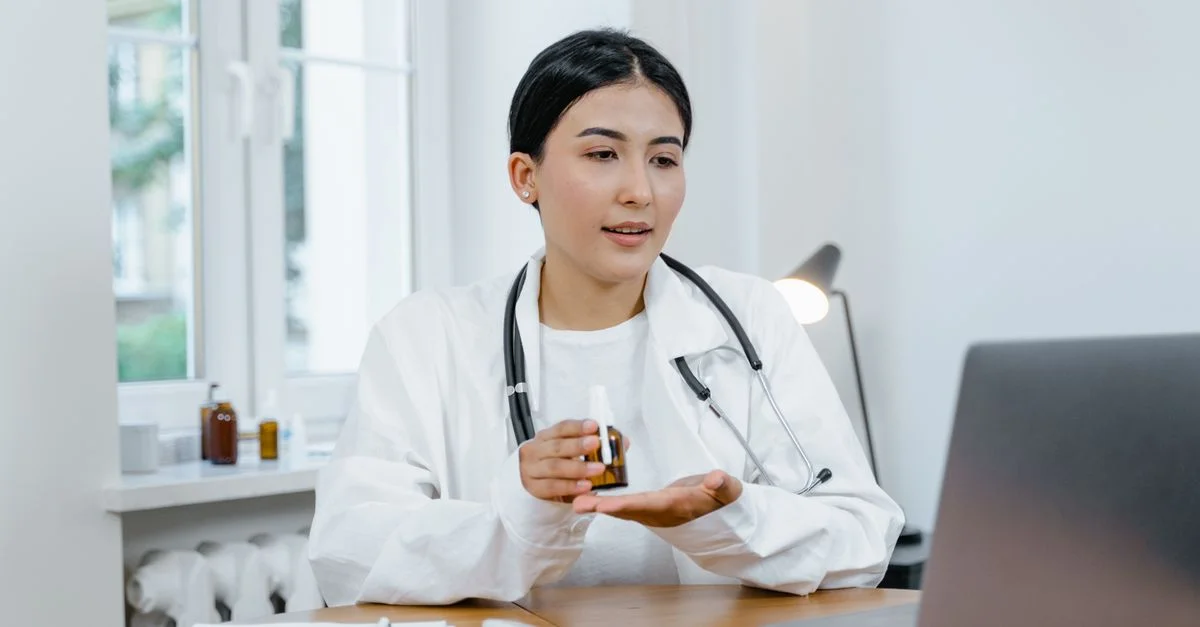 Une jeune médecin en manteau blanc lors d'un appel vidéo, discutant des médicaments avec un patient.